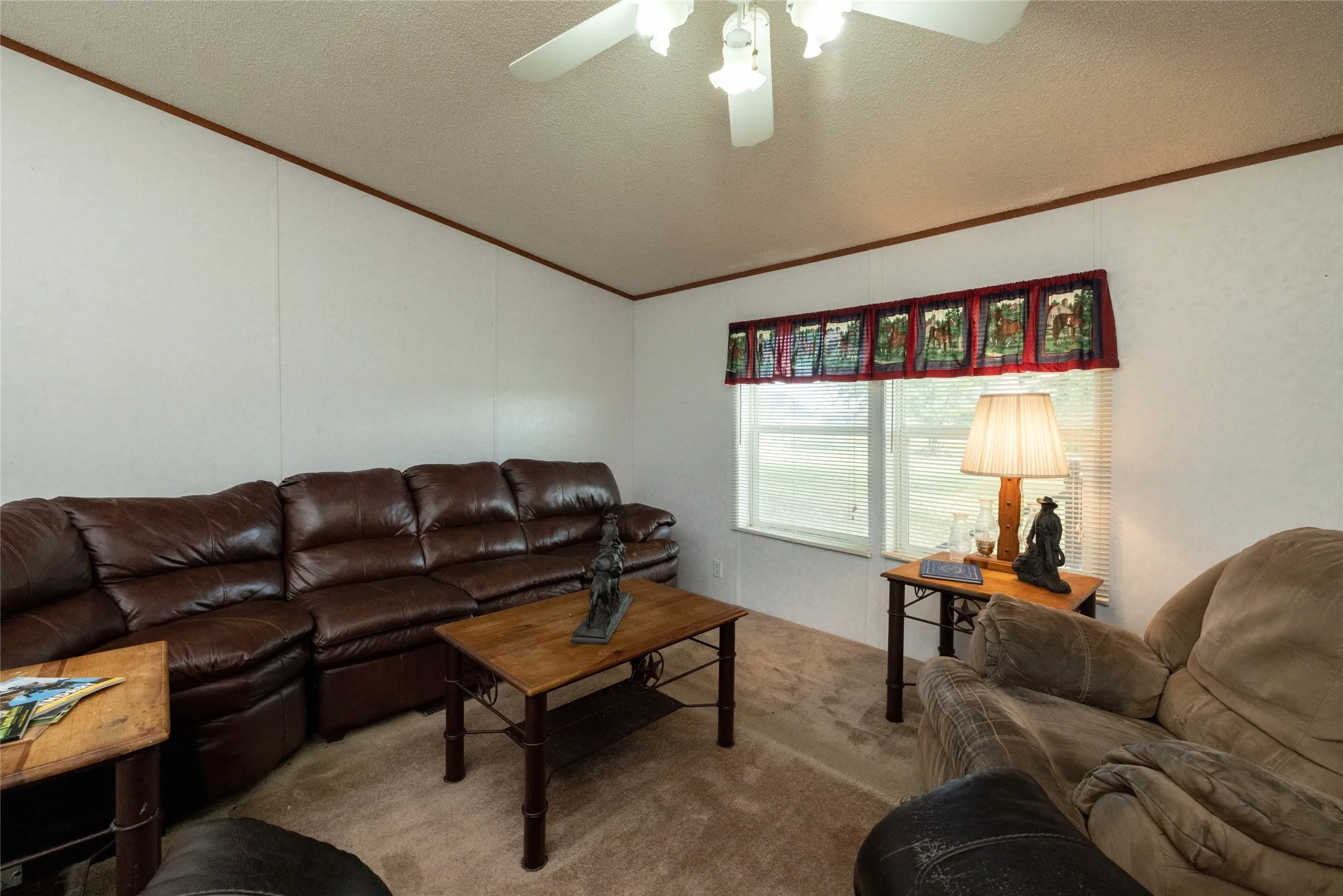Carpeted living room with ceiling fan, a textured ceiling, and crown molding