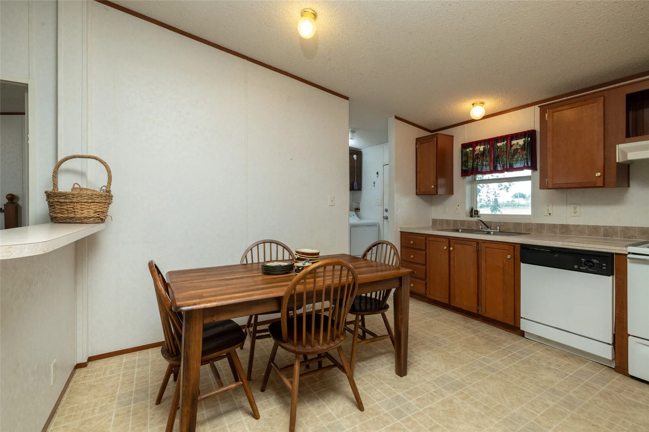 Kitchen with light tile patterned flooring, sink, white appliances, a textured ceiling, and washer / clothes dryer