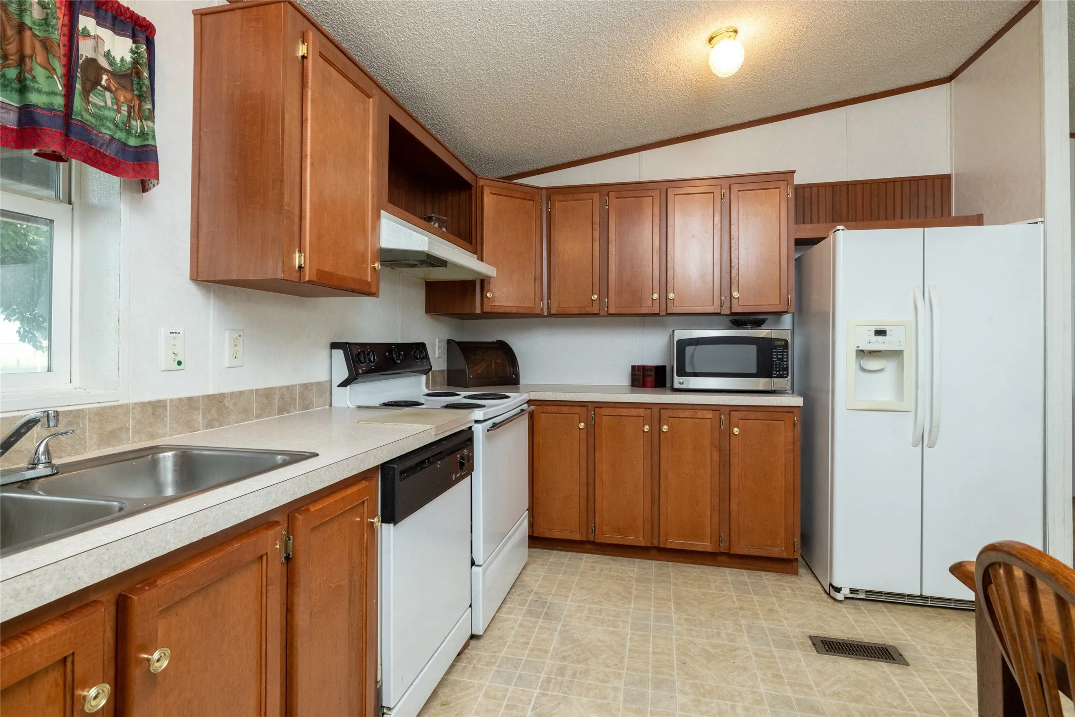 Kitchen featuring vaulted ceiling, light tile patterned floors, sink, a textured ceiling, and white appliances