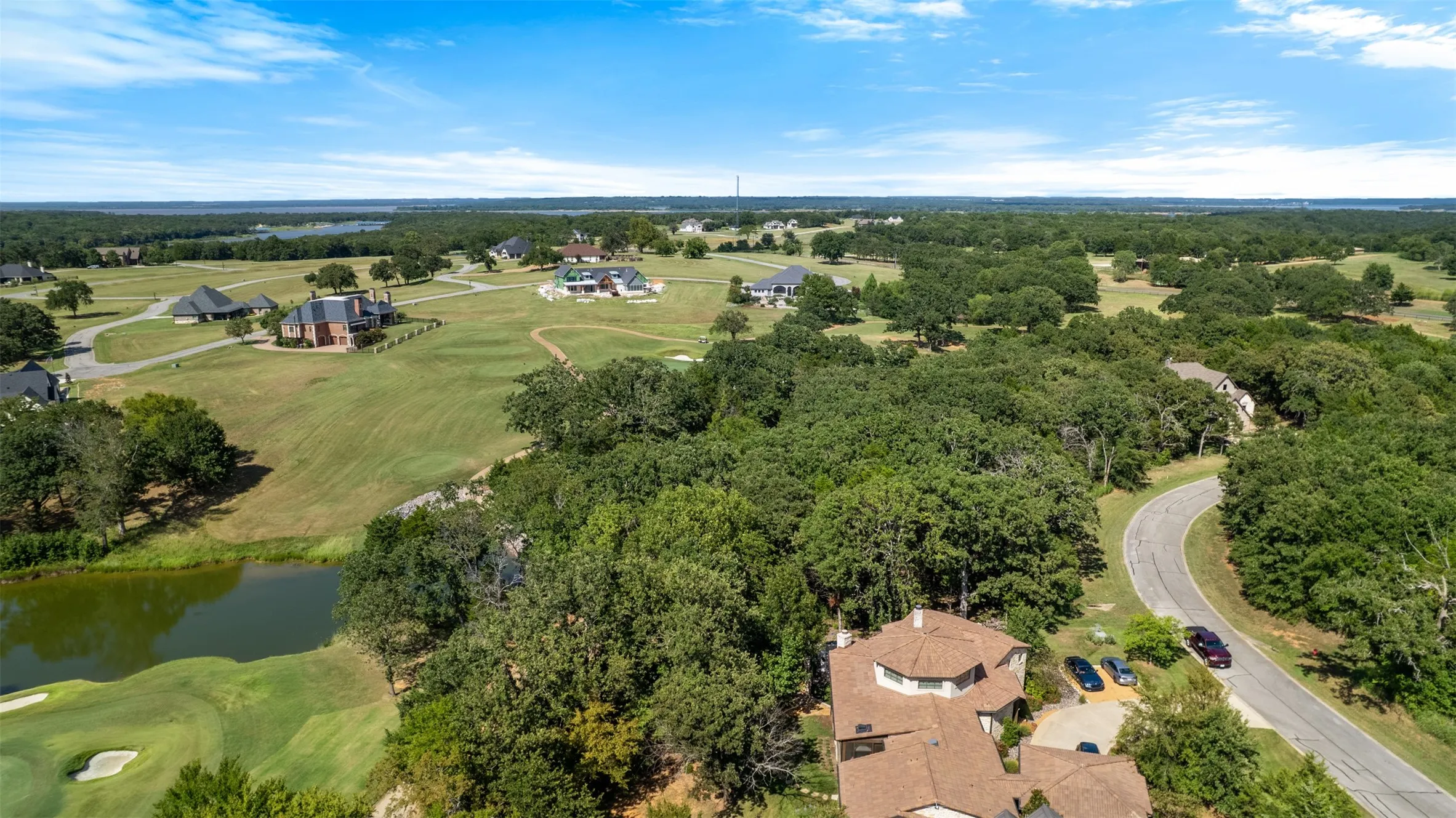 Aerial view of property and surrounding area with a nearby body of water and a golf club