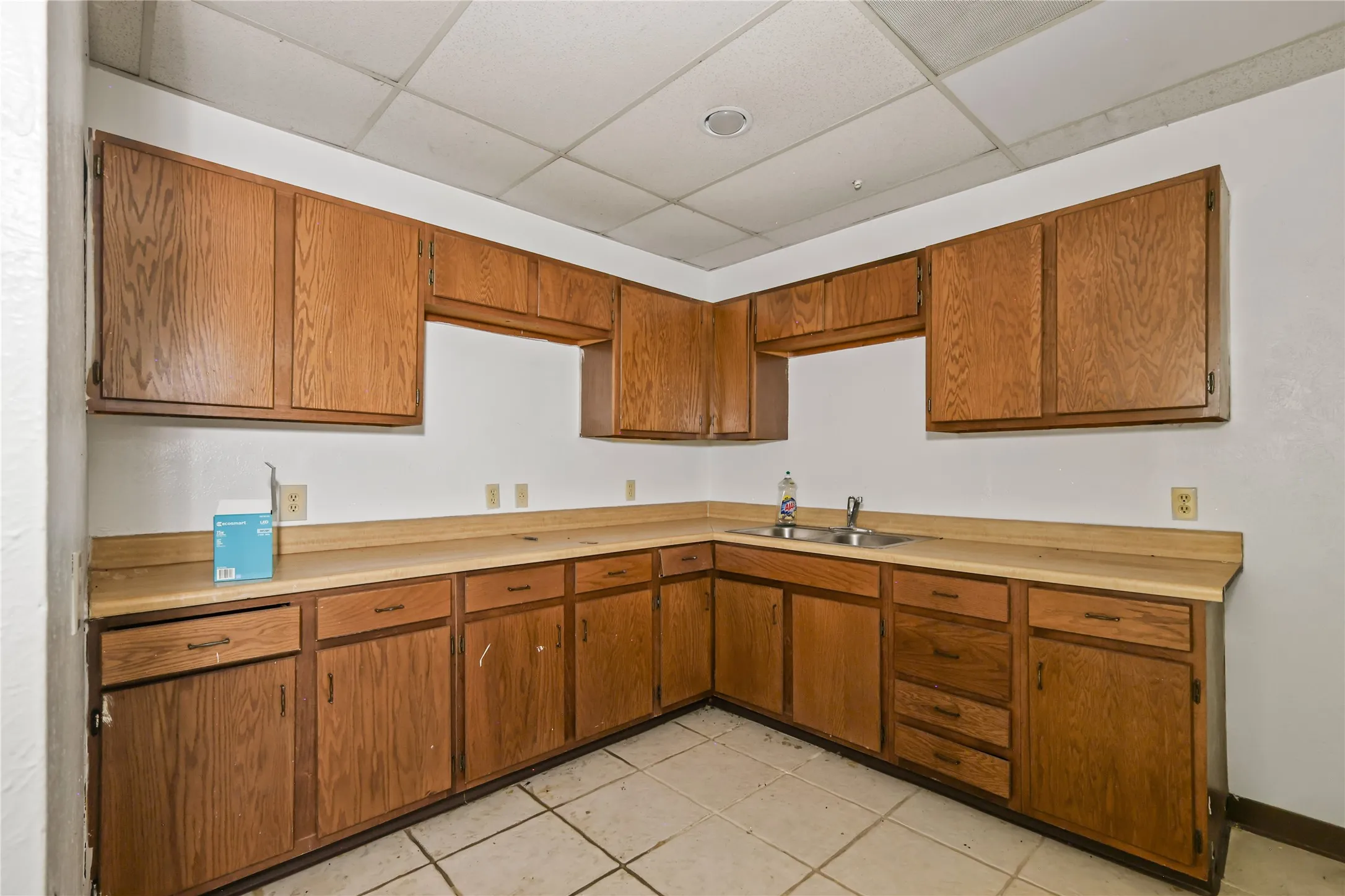 Kitchen with light tile patterned flooring, sink, and a drop ceiling