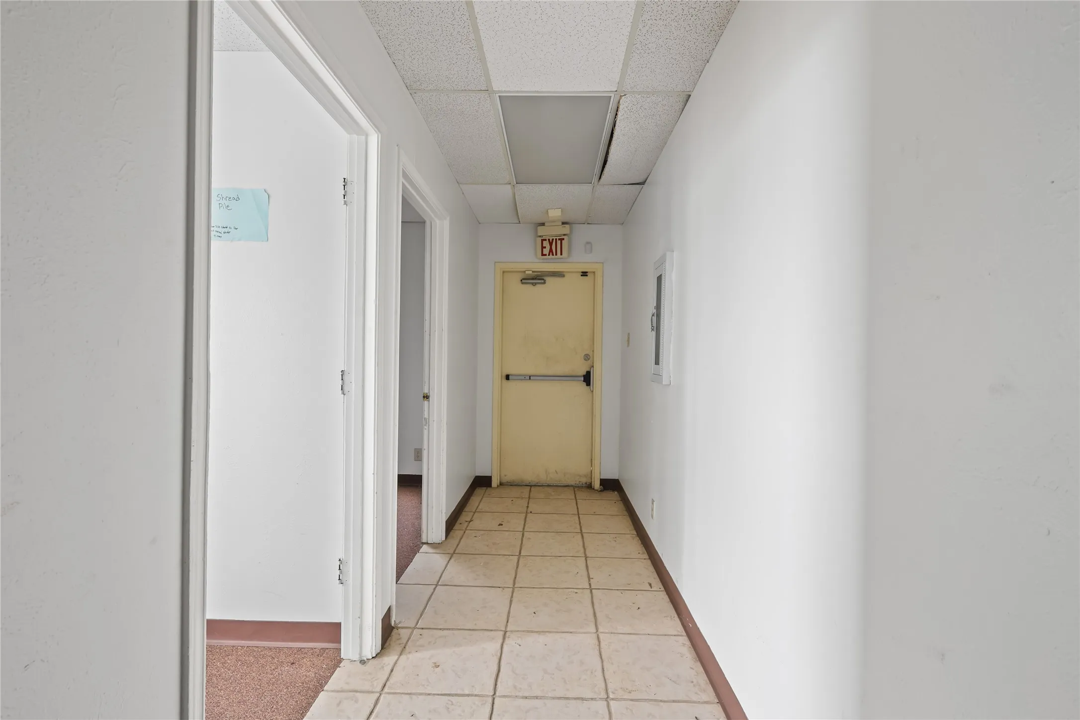 Hall with a paneled ceiling and light tile patterned floors