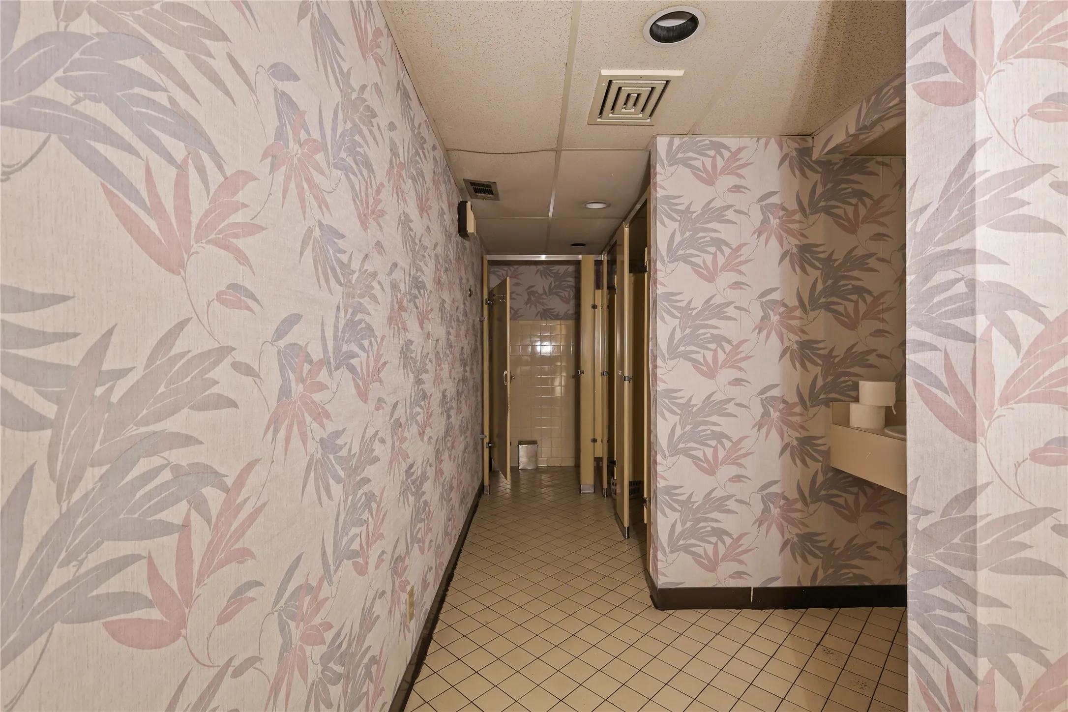 Hallway with light tile patterned floors and a drop ceiling