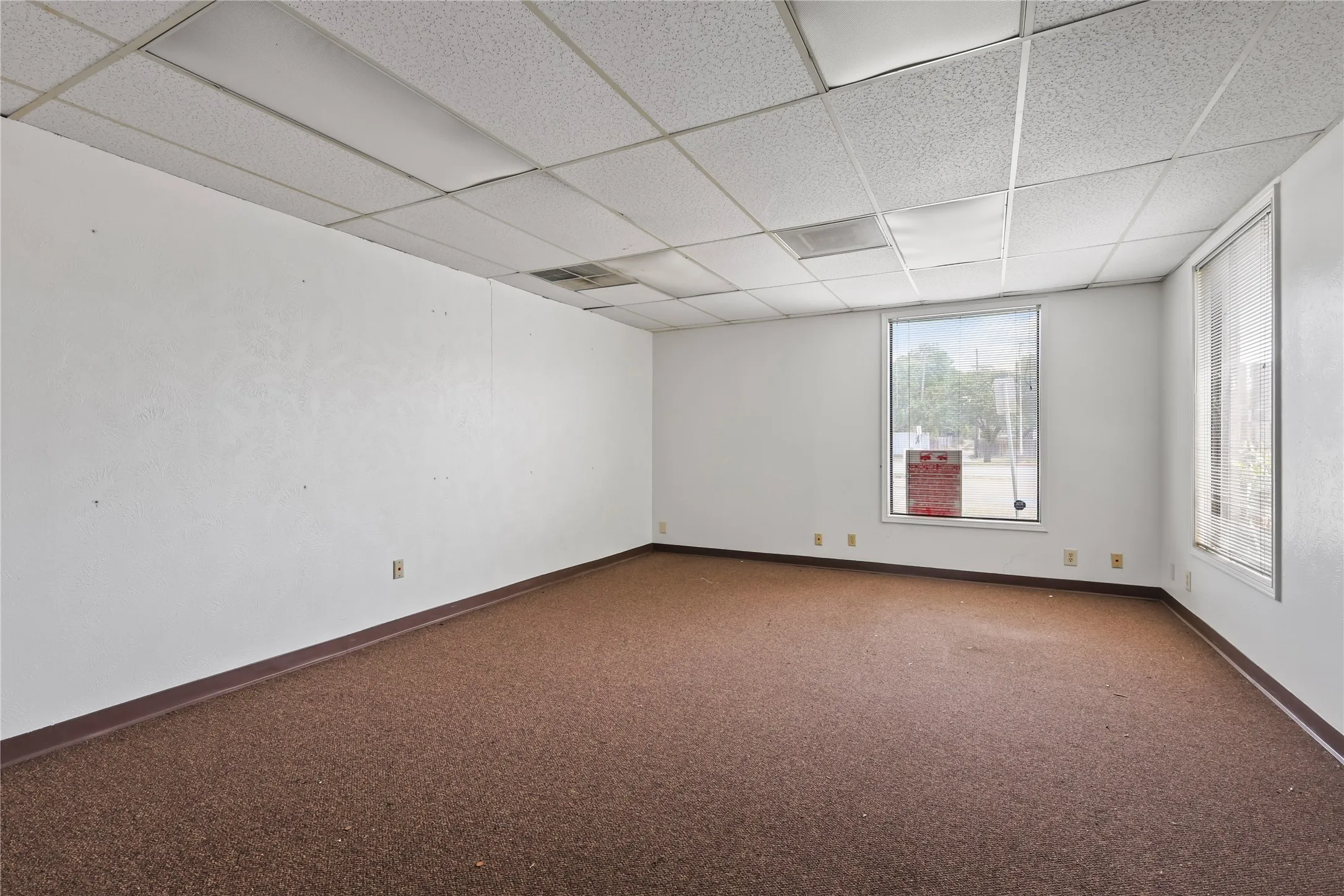 Carpeted floor, dropped ceiling with  tiles.  Has florescent lighting.