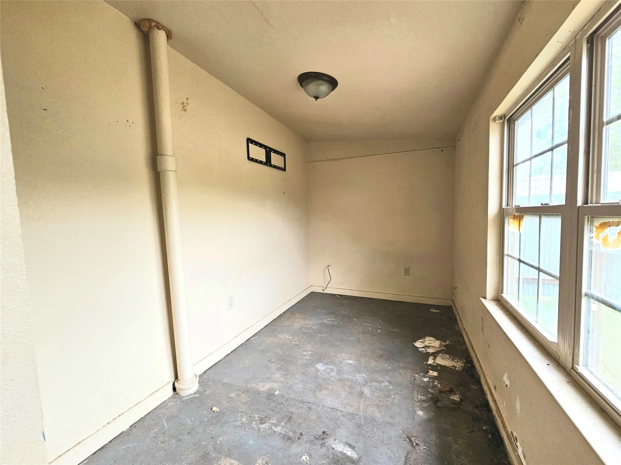 Unfurnished room with unfinished concrete flooring