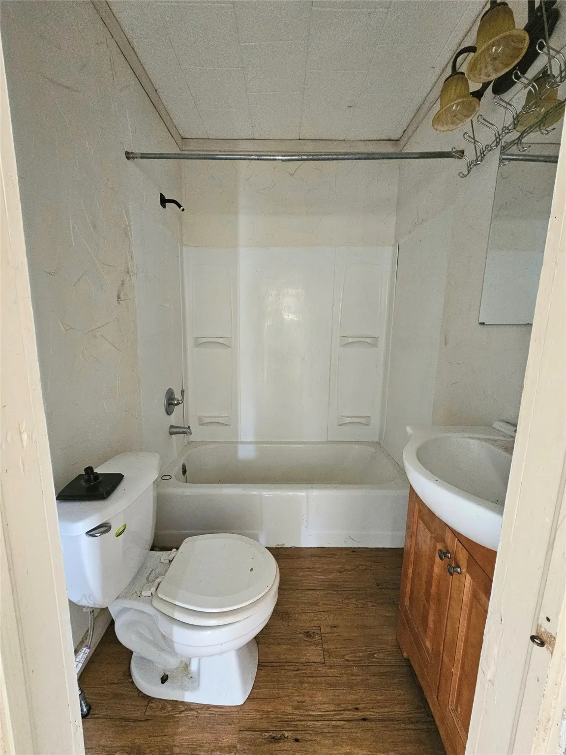 Full bathroom with washtub / shower combination, toilet, and wood finished floors