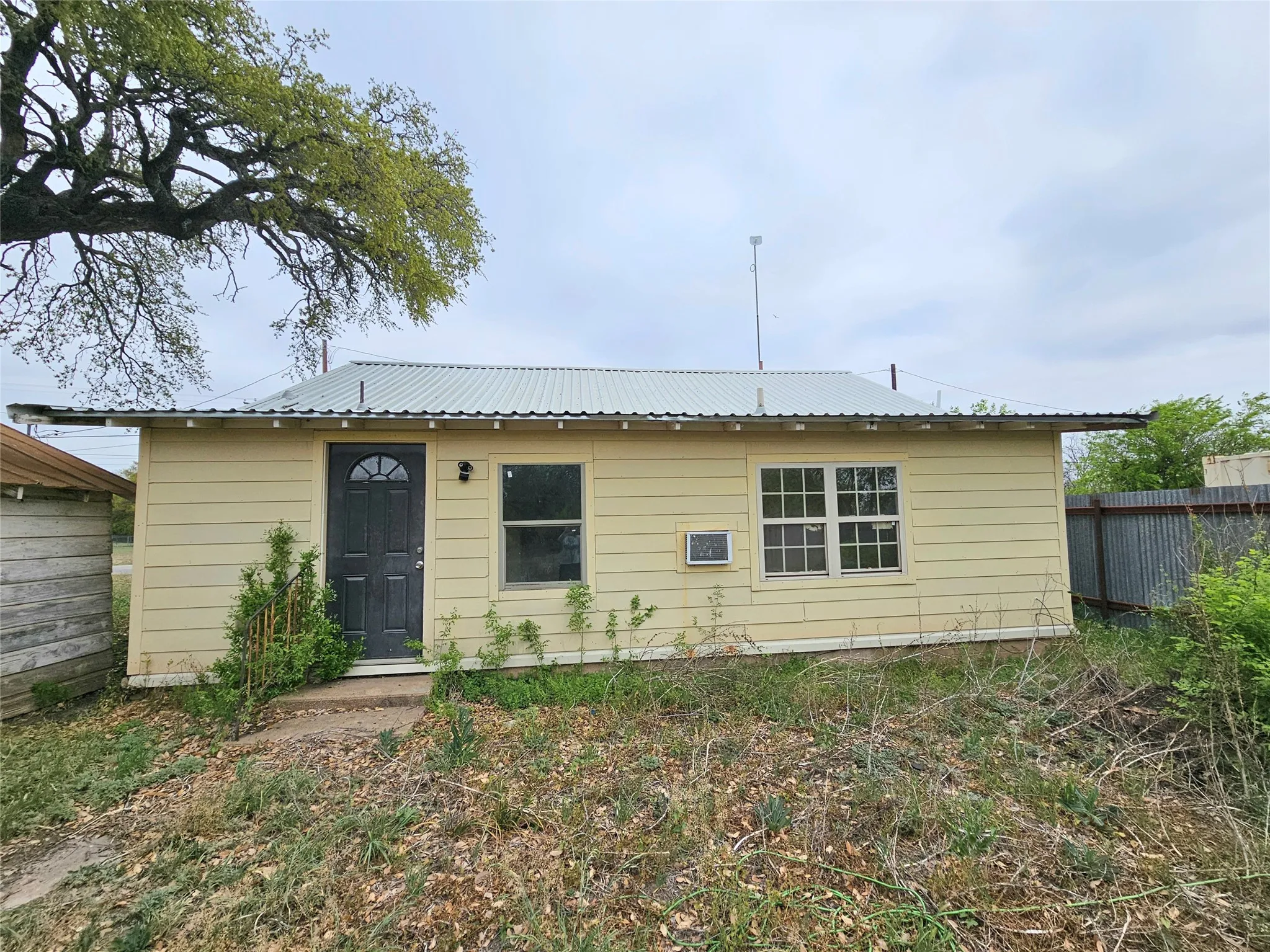 Rear view of property with metal roof and fence