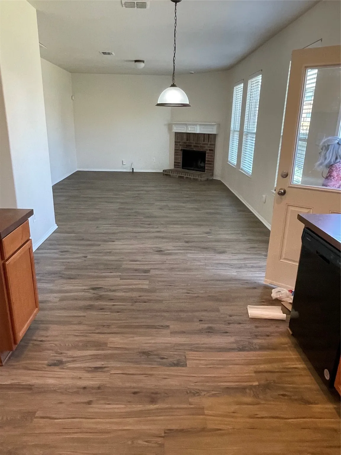 Unfurnished living room featuring wood-type flooring and a brick fireplace
