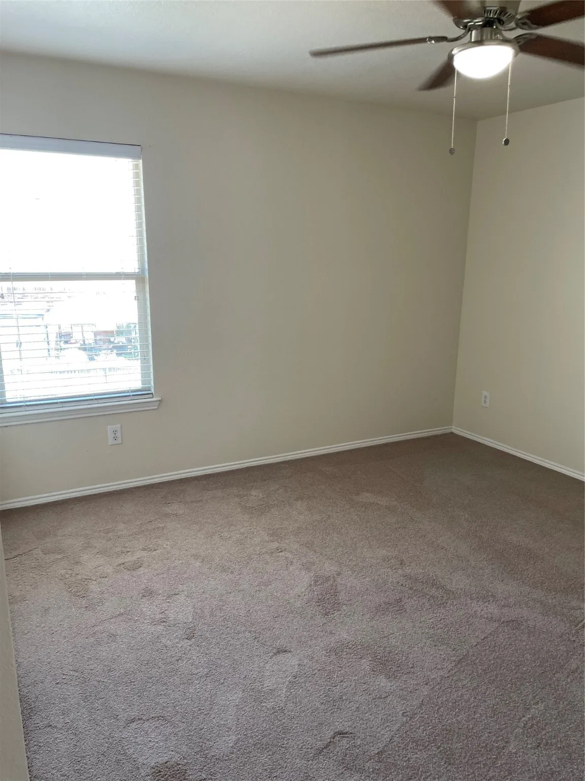 Carpeted empty room featuring ceiling fan