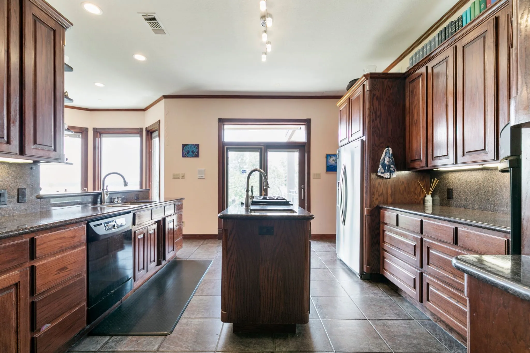 Kitchen with dishwasher, backsplash, stainless steel fridge with ice dispenser, a kitchen island with sink, and sink