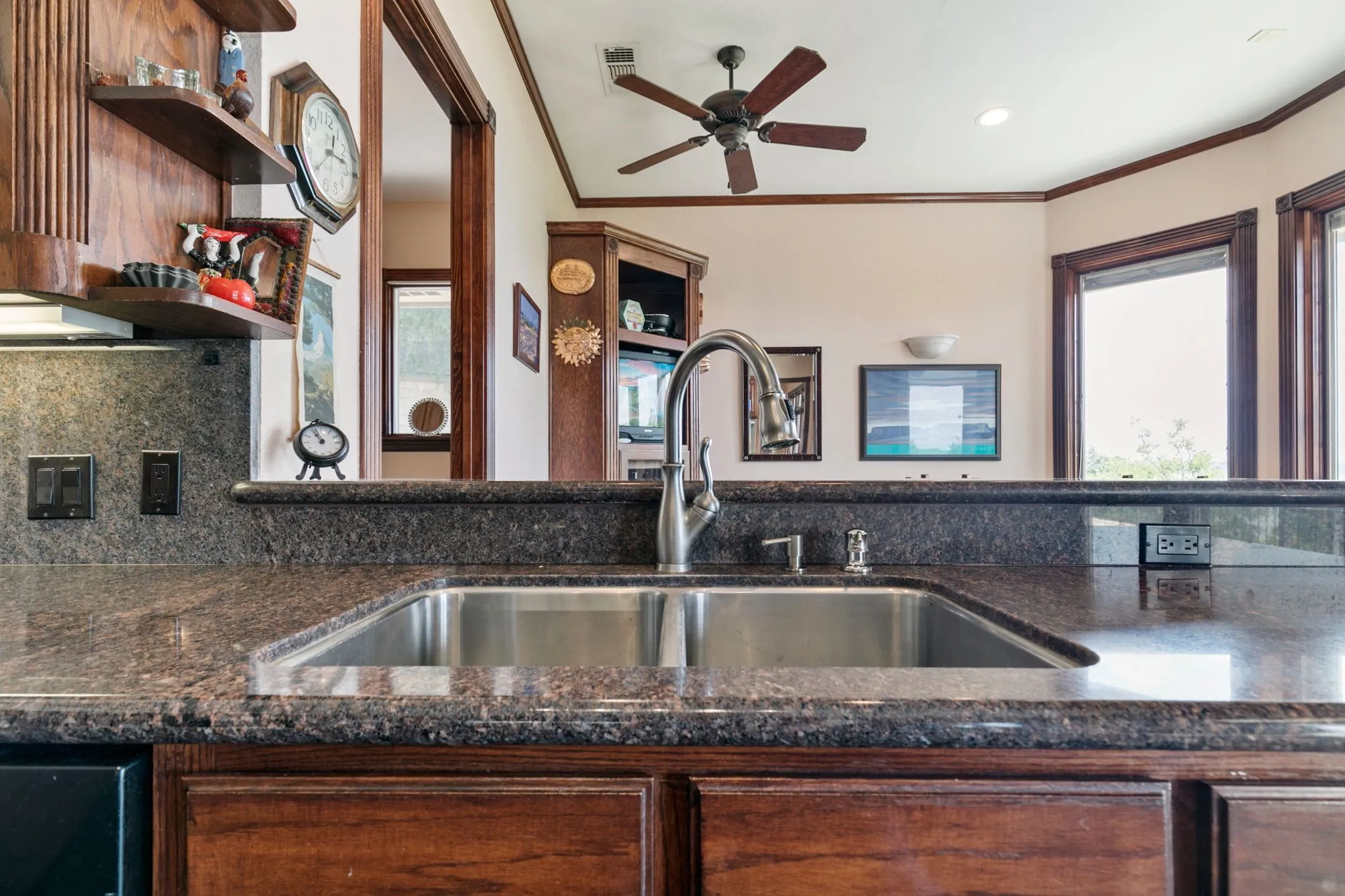 Kitchen featuring ornamental molding, ceiling fan, sink, and dark stone countertops