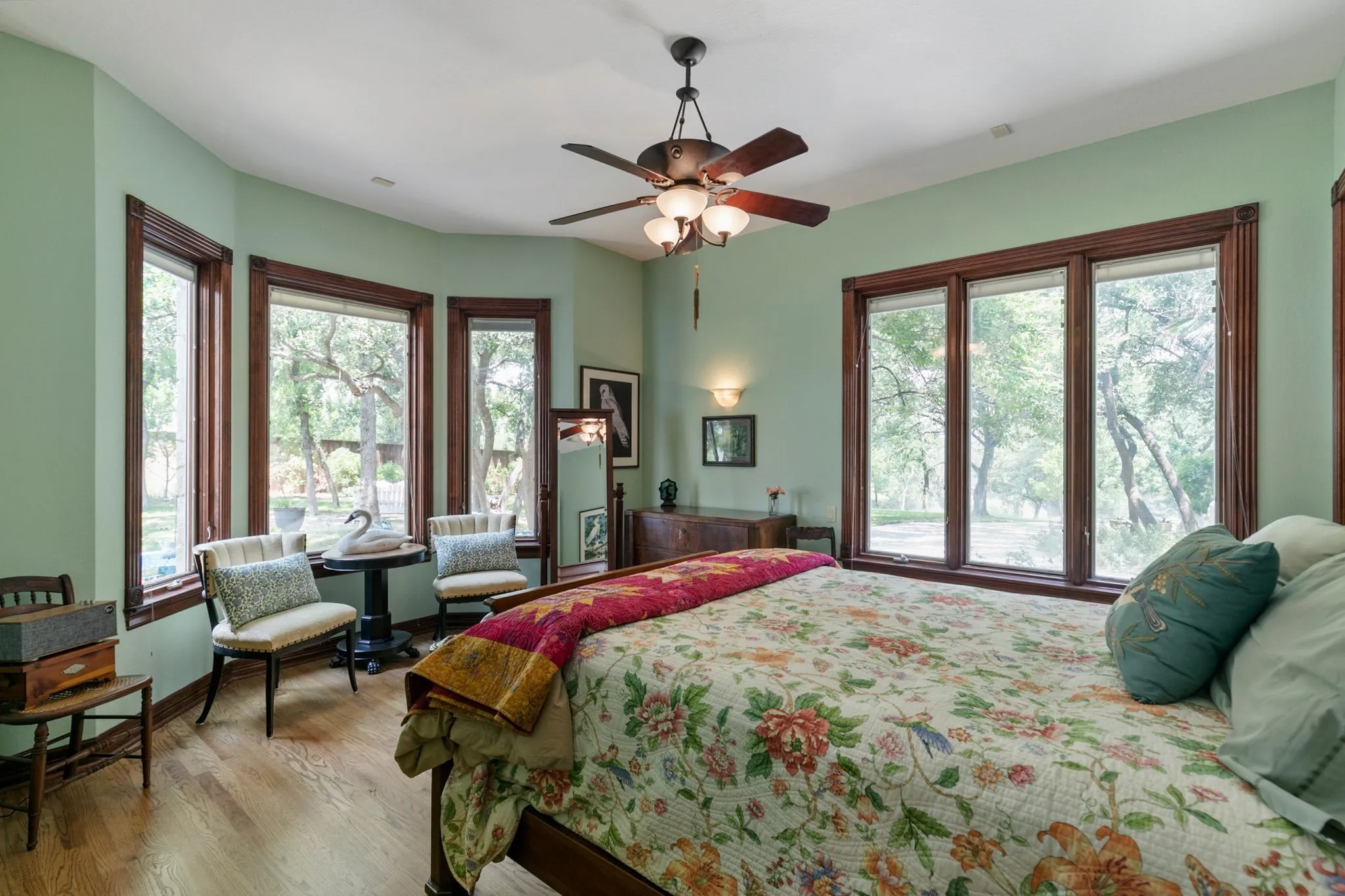 Bedroom with ceiling fan, light wood-type flooring, and multiple windows