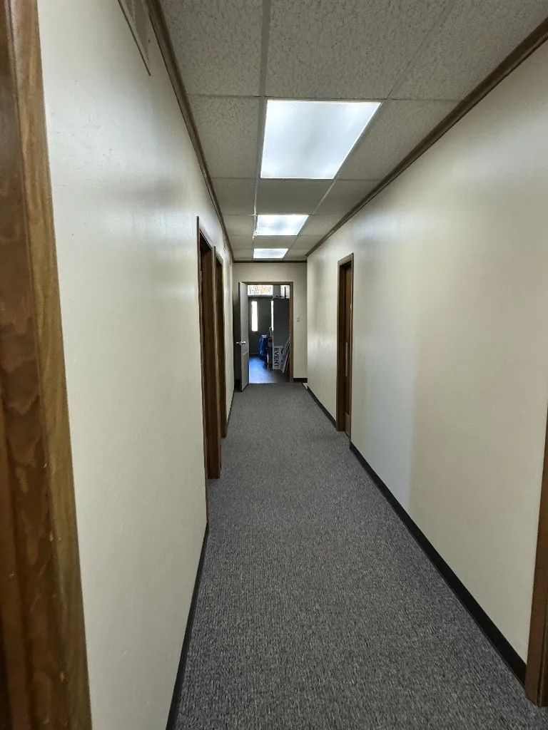 Corridor with dark carpet and a paneled ceiling