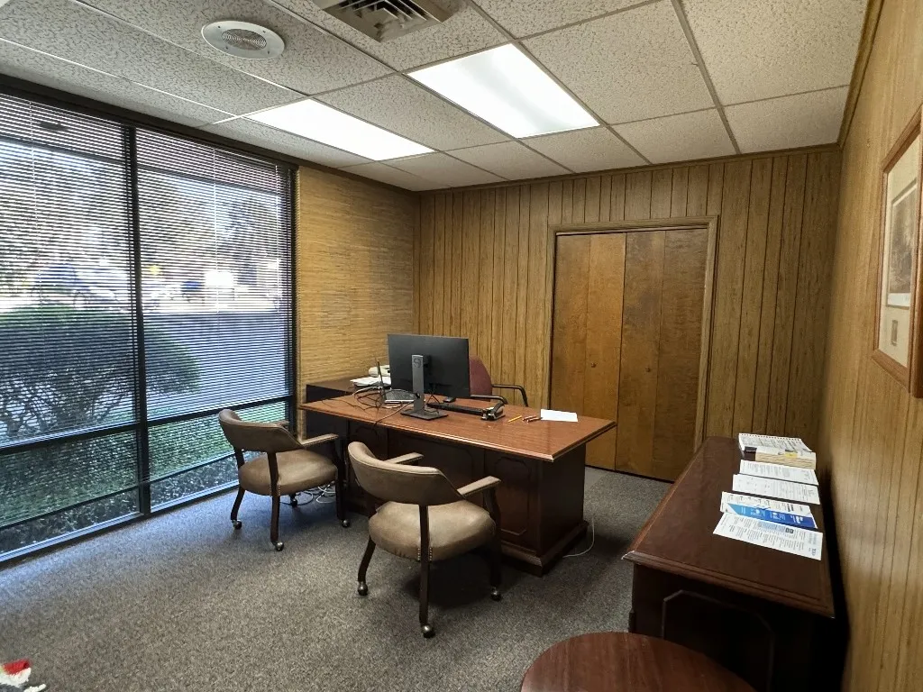 Carpeted office featuring wooden walls and a paneled ceiling