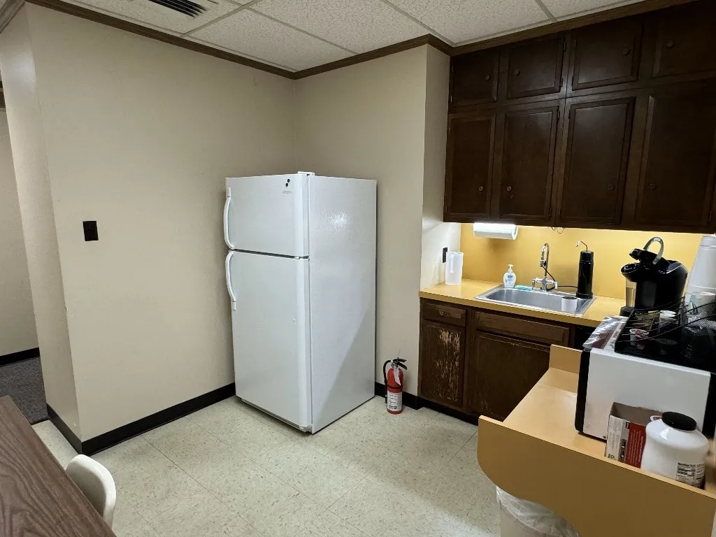 Kitchen with a drop ceiling, dark brown cabinets, white refrigerator, and sink