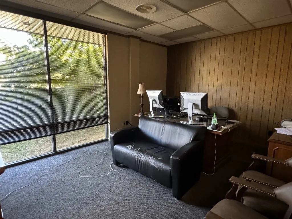 Carpeted home office featuring a drop ceiling and wooden walls