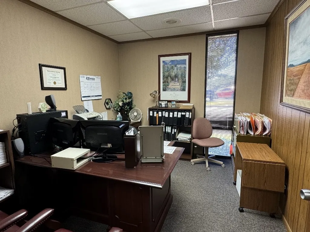 Office area featuring a paneled ceiling, carpet flooring, and wood walls