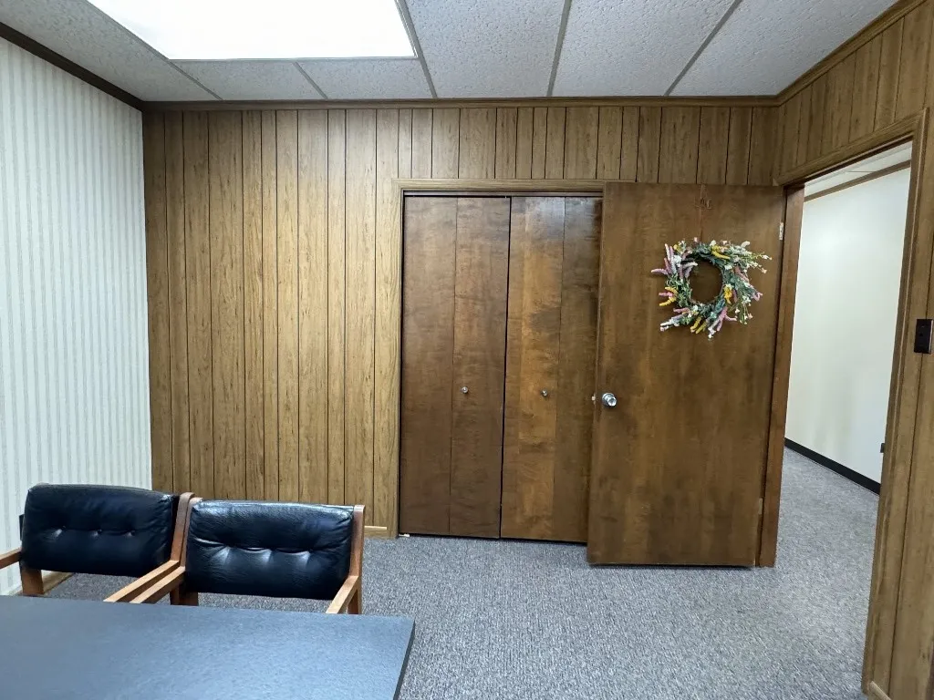 Home office featuring a drop ceiling, wooden walls, and light carpet