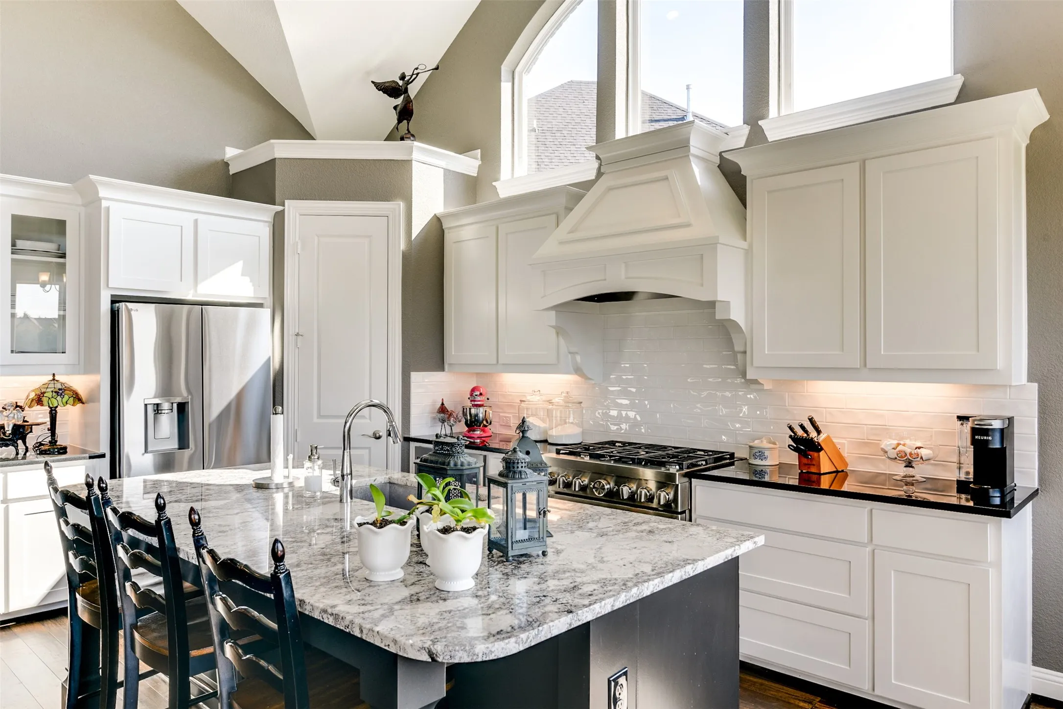 Kitchen with a kitchen island with sink, lofted ceiling, stainless steel appliances, dark hardwood / wood-style flooring, and premium range hood