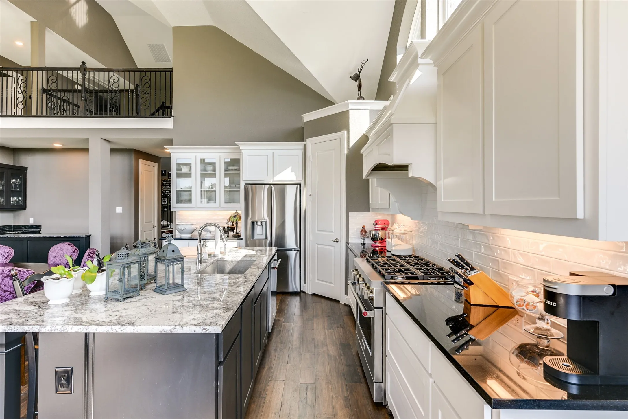 Kitchen with appliances with stainless steel finishes, dark wood-type flooring, an island with sink, white cabinets, and sink