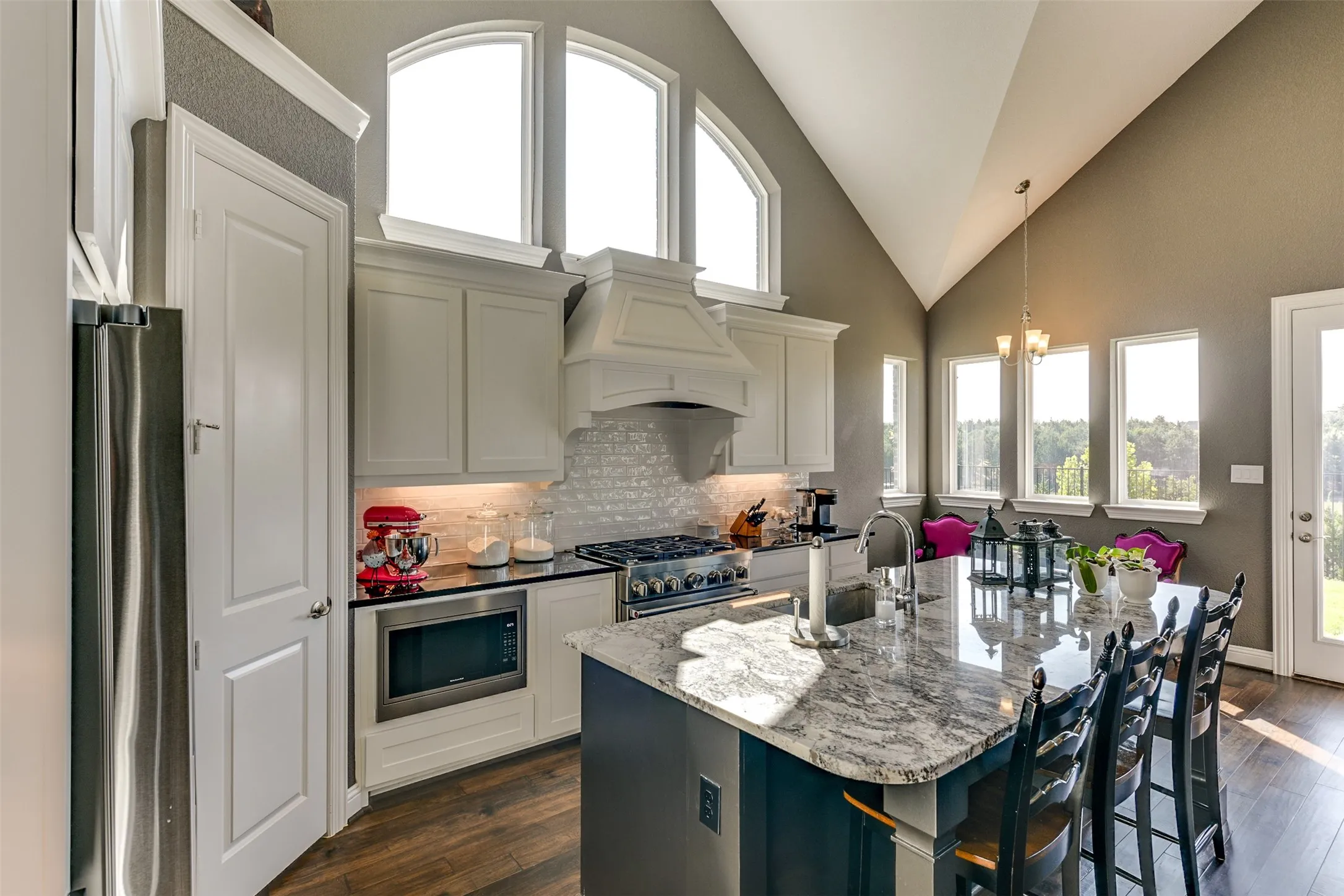 Kitchen with light stone countertops, appliances with stainless steel finishes, dark hardwood / wood-style flooring, and a healthy amount of sunlight