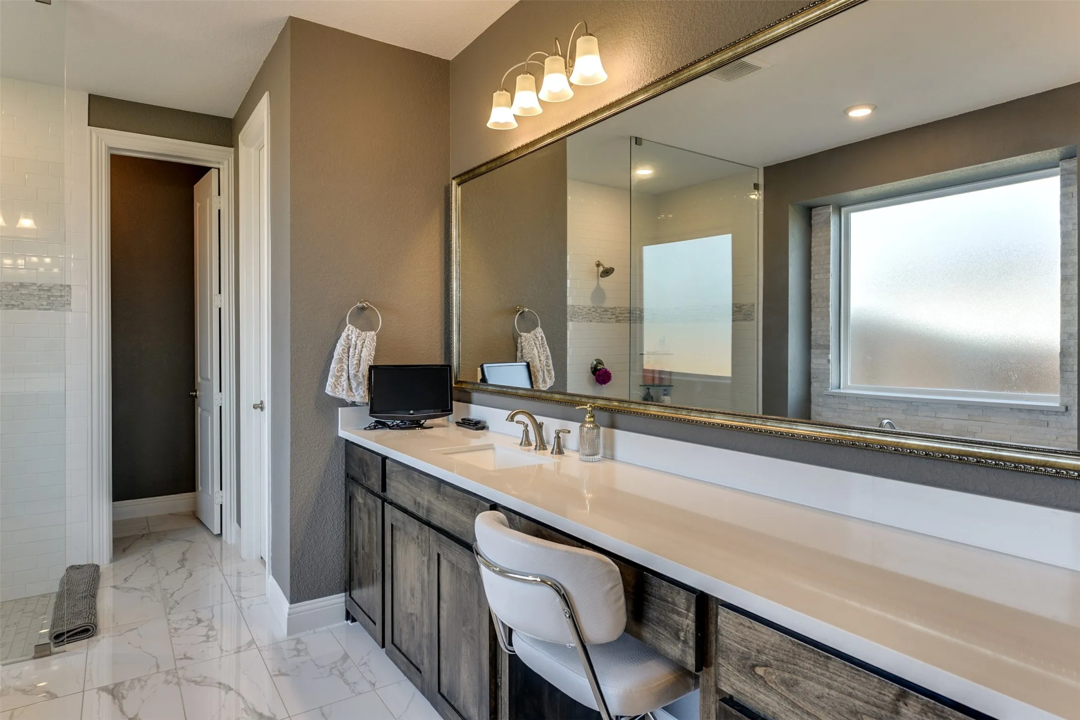 Bathroom featuring a tile shower and vanity.  One of the dual sinks is pictured.  This leads to a huge walk-in closet