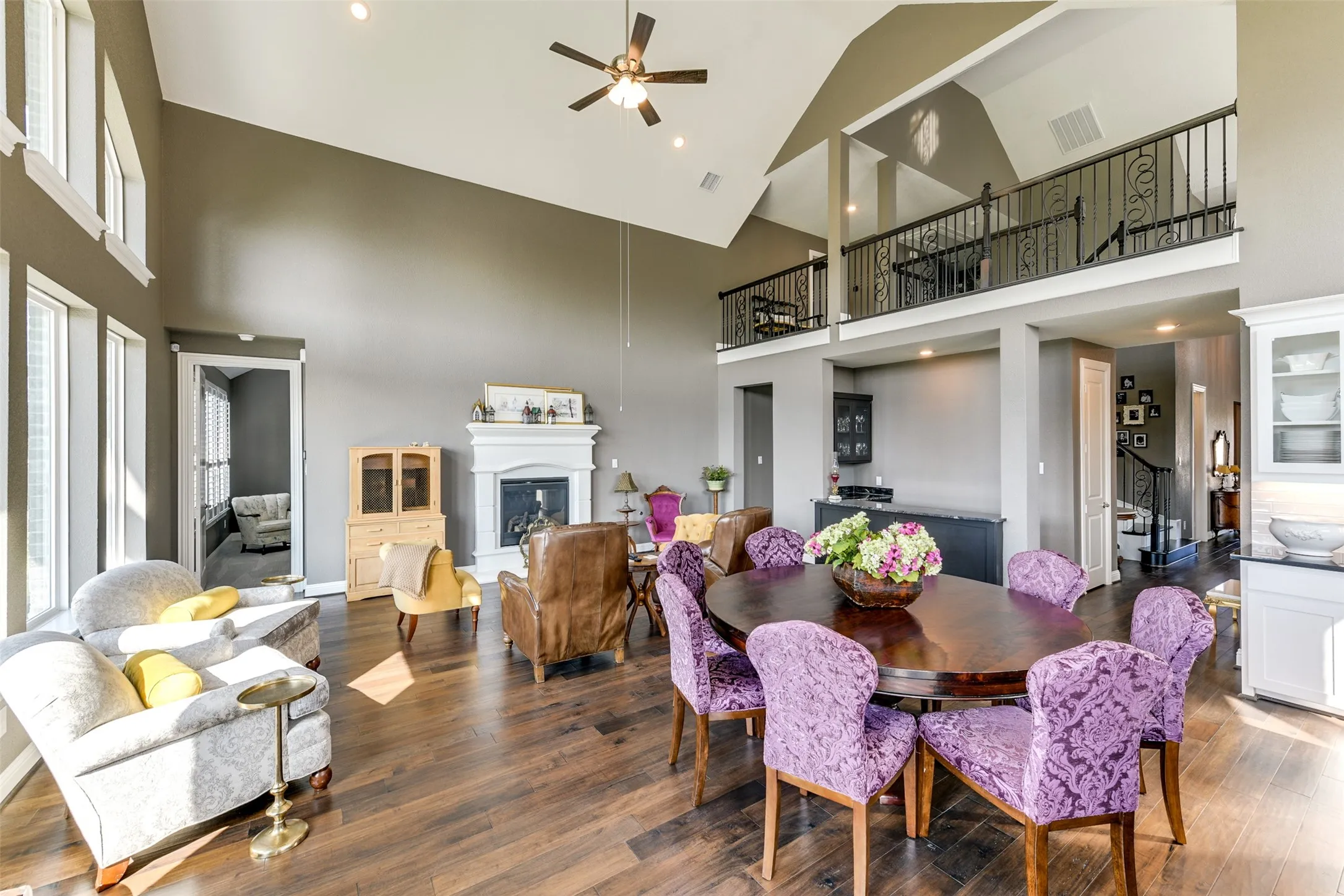 Dining space featuring high vaulted ceiling, ceiling fan, and hardwood / wood-style flooring.  Opens to the family room, and twenty foot ceilings open to the upstairs loft.
