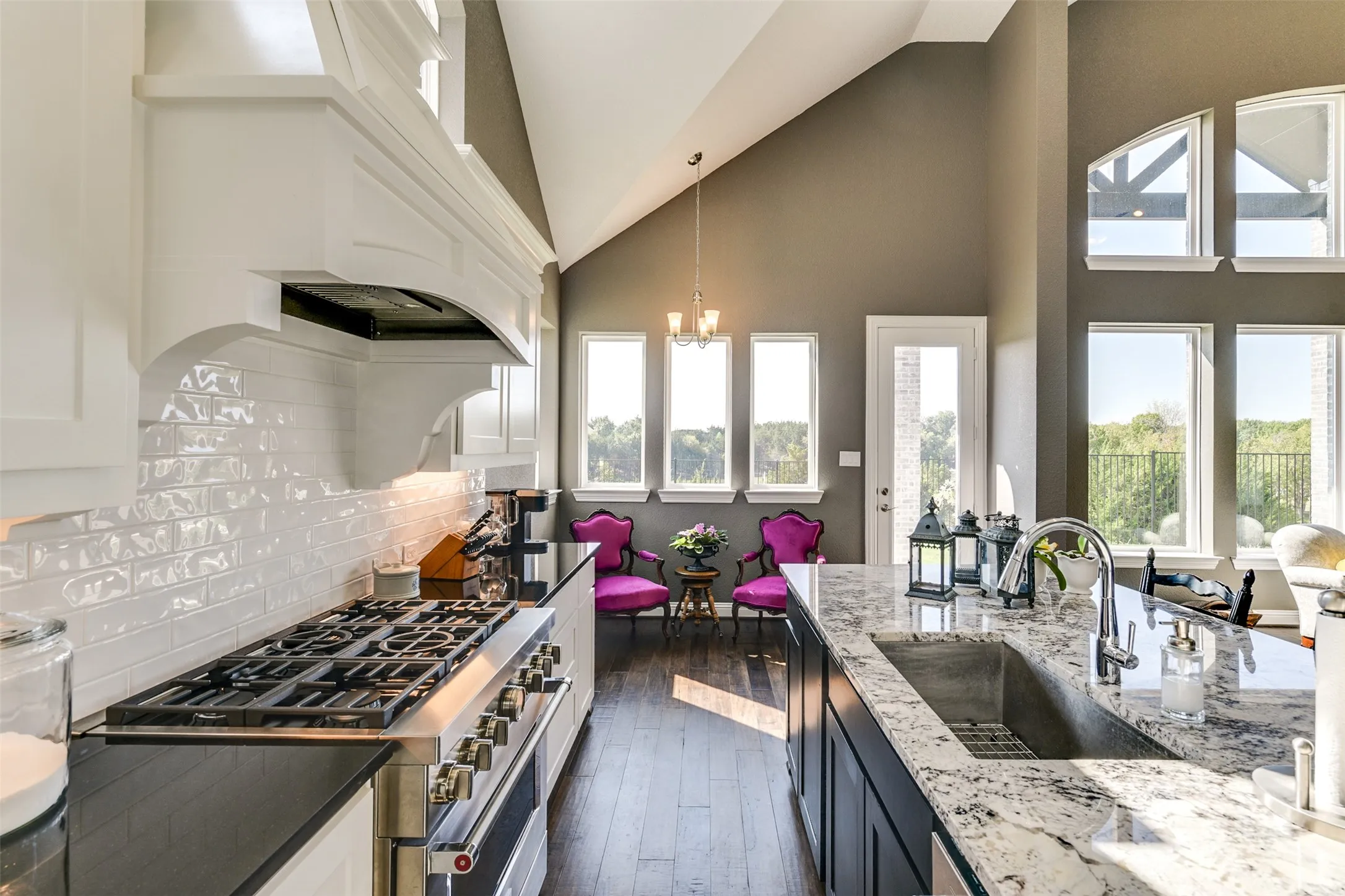 Kitchen featuring dark hardwood / wood-style floors, sink, white cabinetry, decorative backsplash, and stainless steel range.  More vies.