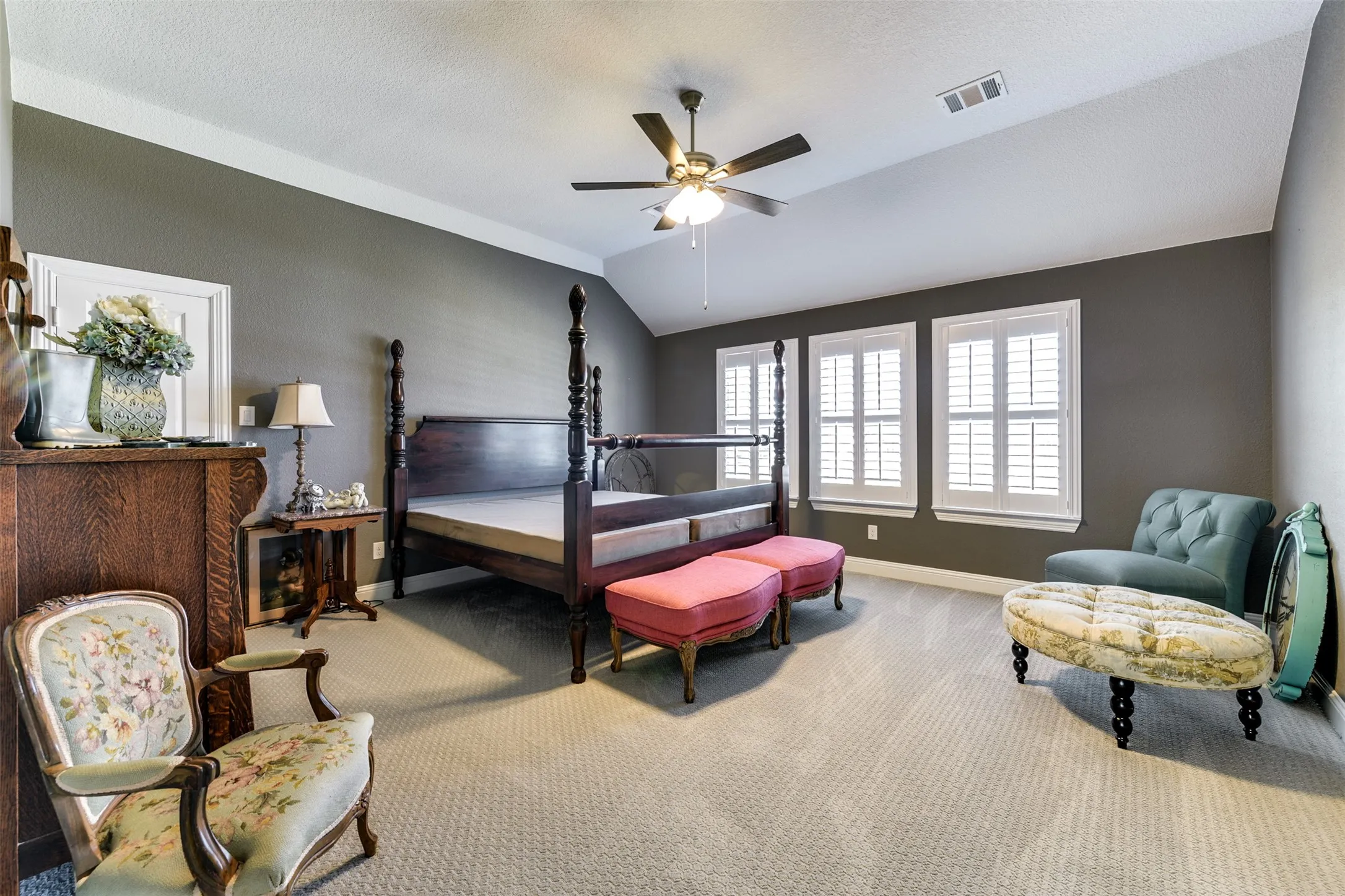 One of two bedrooms upstairs, featuring vaulted ceiling, ceiling fan, and light colored carpet