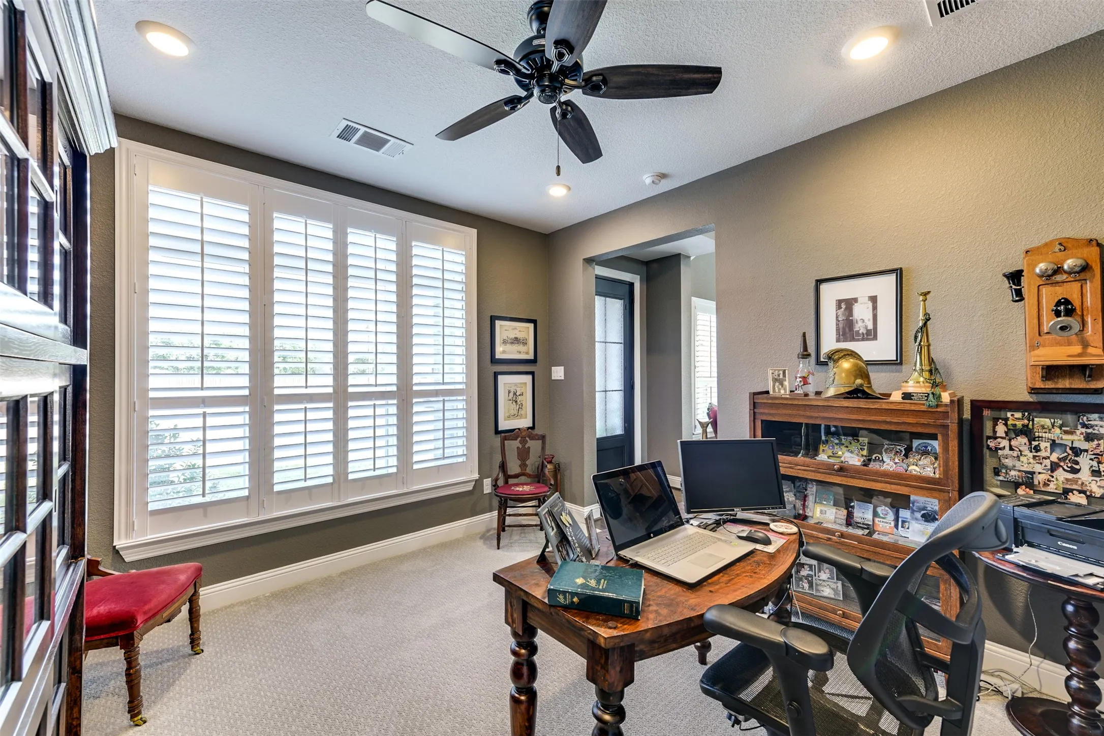 Carpeted home office with a textured ceiling, ceiling fan, and a wealth of natural light