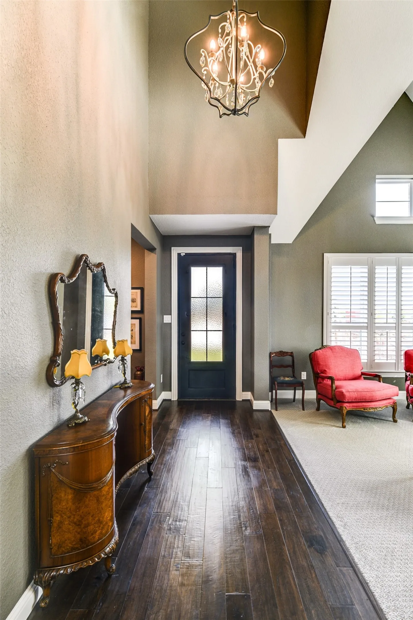 Entryway featuring a high ceiling, plenty of natural light, and dark hardwood / wood-style floors.  This opens up to the formal living room on the right.