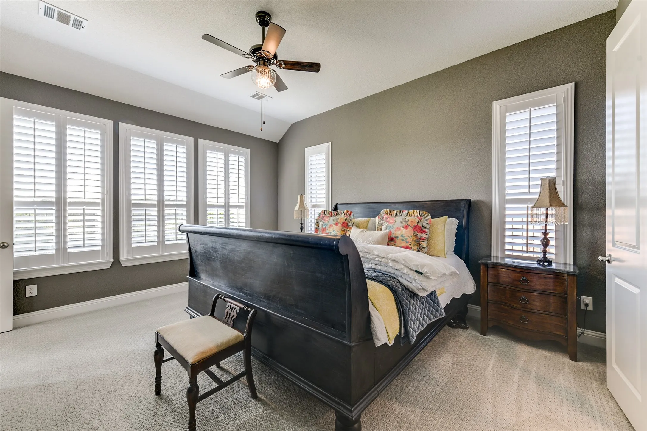 Carpeted bedroom with vaulted ceiling and ceiling fan