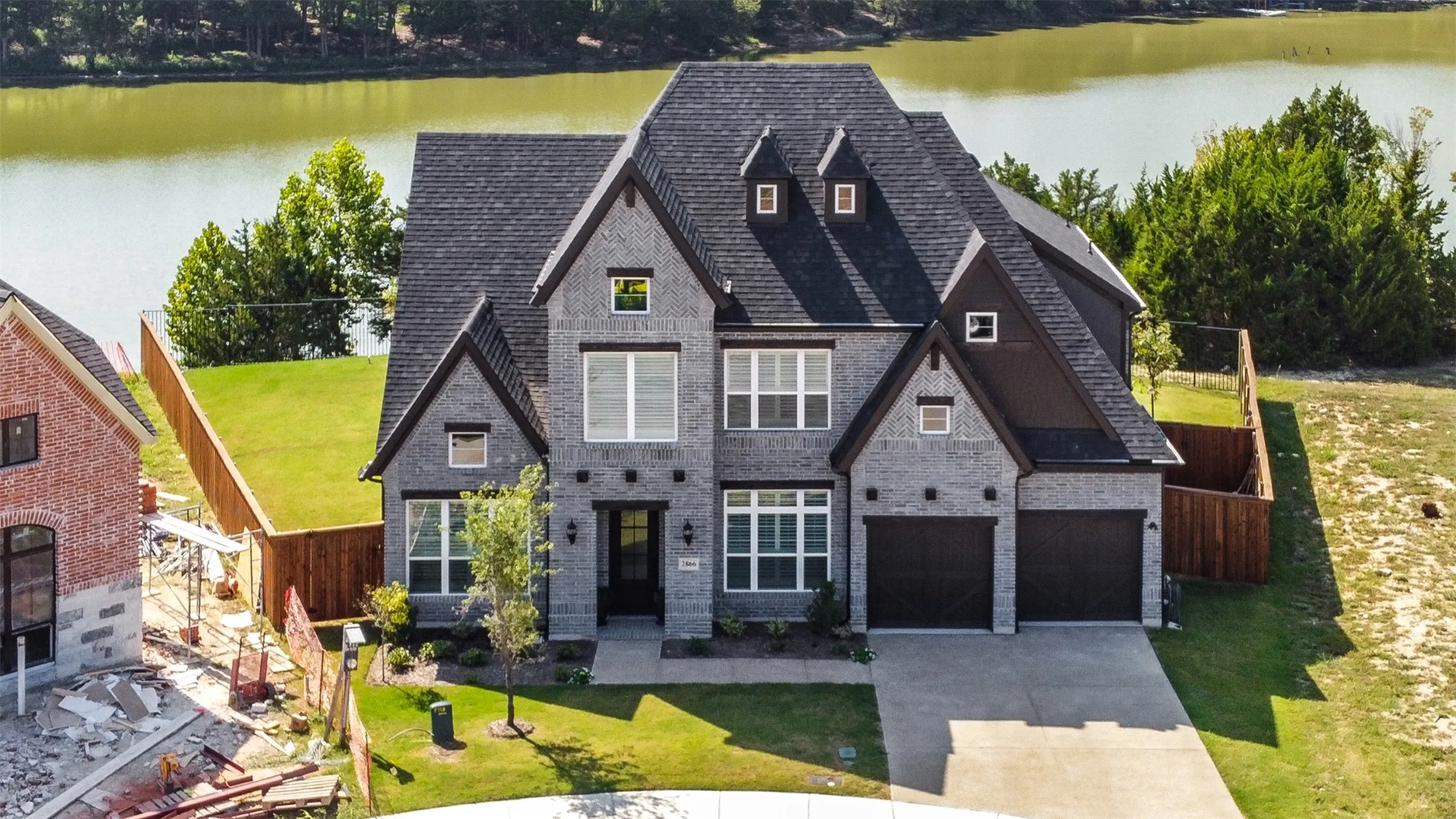 View of front of house with a garage, a water view, and a front lawn