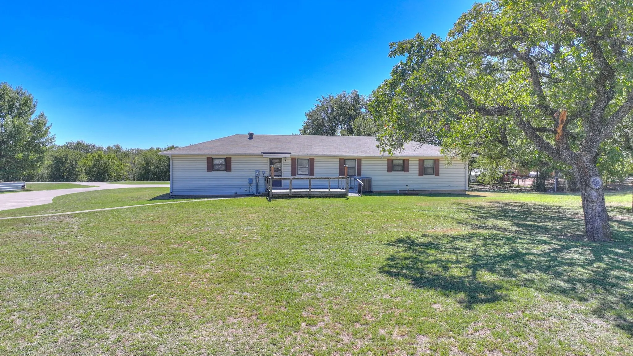 Ranch-style house with a front lawn and a wooden deck