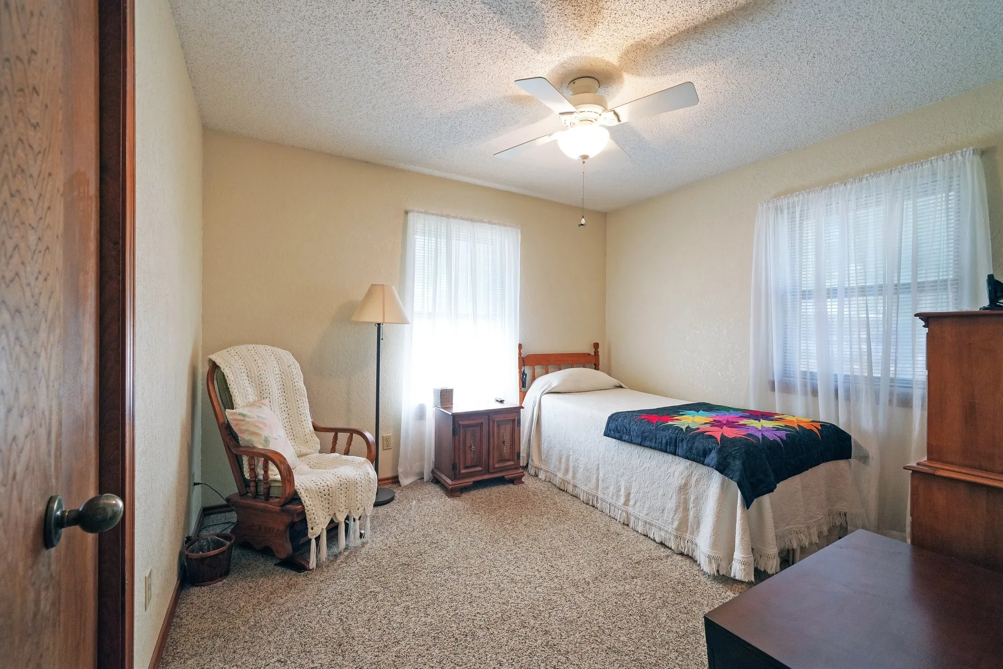 Carpeted bedroom featuring a textured ceiling and ceiling fan