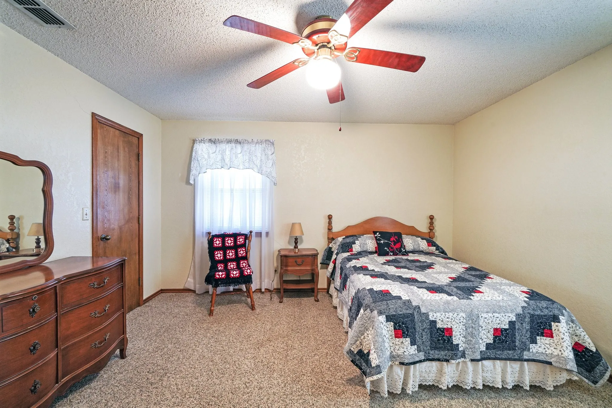 Carpeted bedroom featuring ceiling fan and a textured ceiling