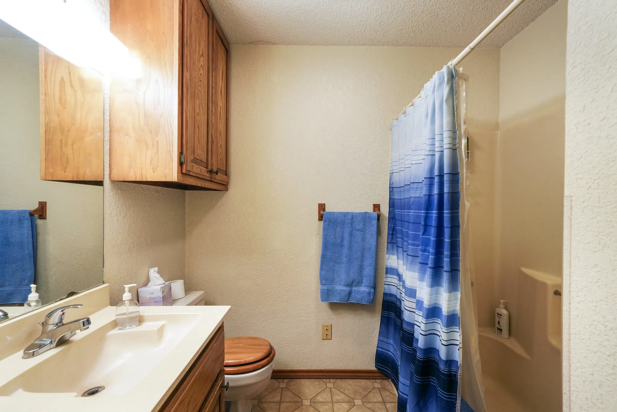 Full bathroom featuring vanity, toilet, a textured ceiling, and shower / bath combo