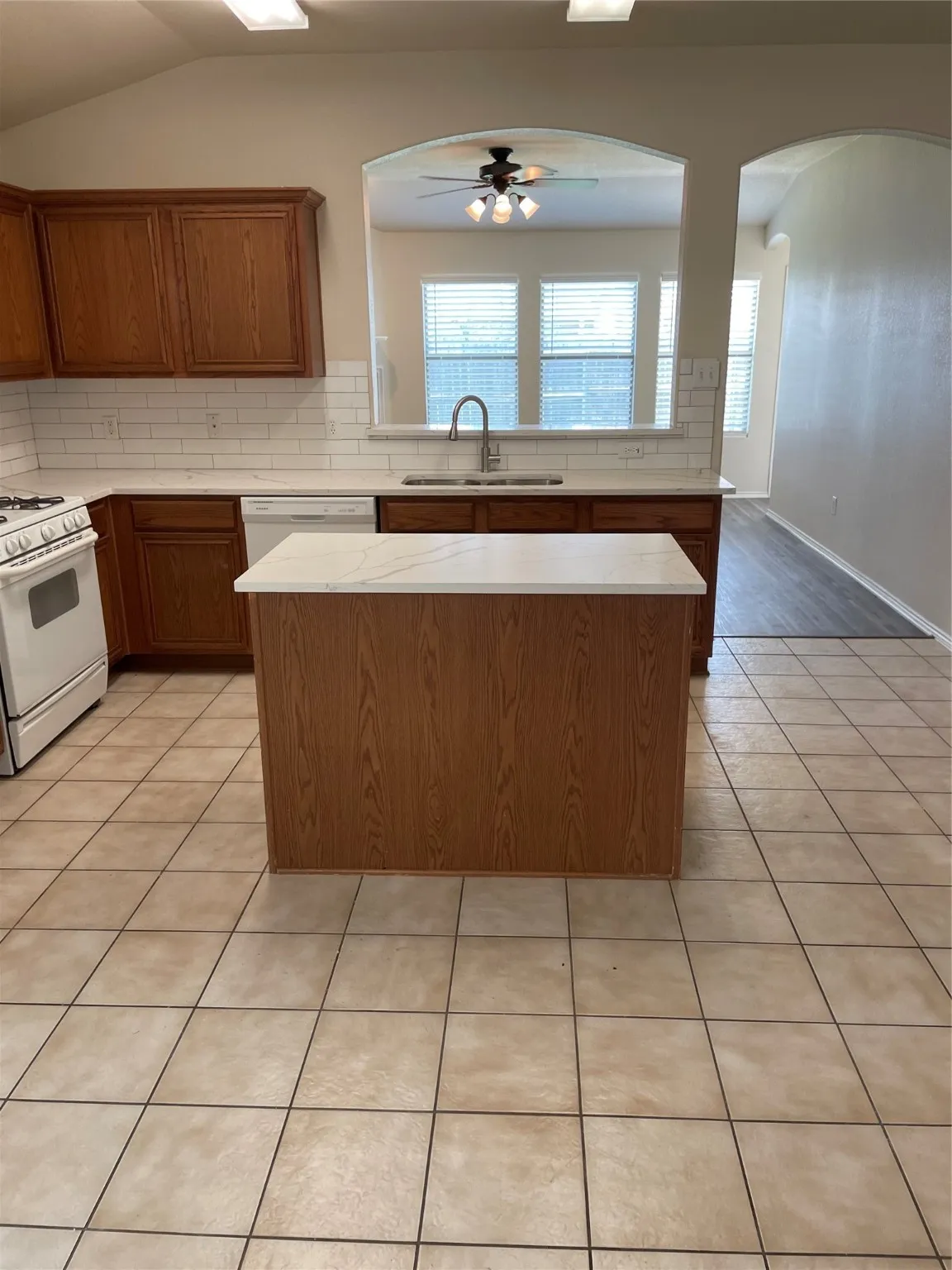 Kitchen featuring ceiling fan, stove, light tile patterned floors, sink, and dishwasher