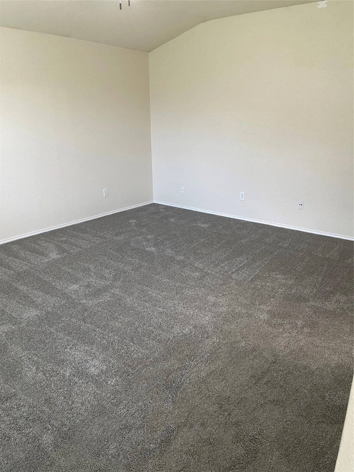 Carpeted empty room featuring lofted ceiling