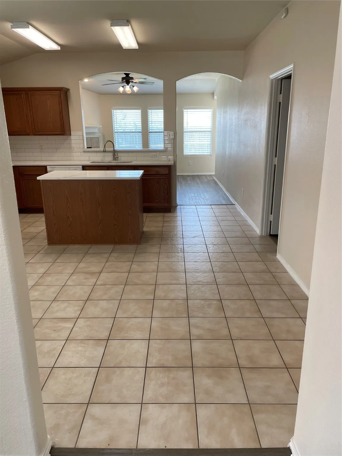 Kitchen with sink, kitchen peninsula, decorative backsplash, light tile patterned floors, and ceiling fan