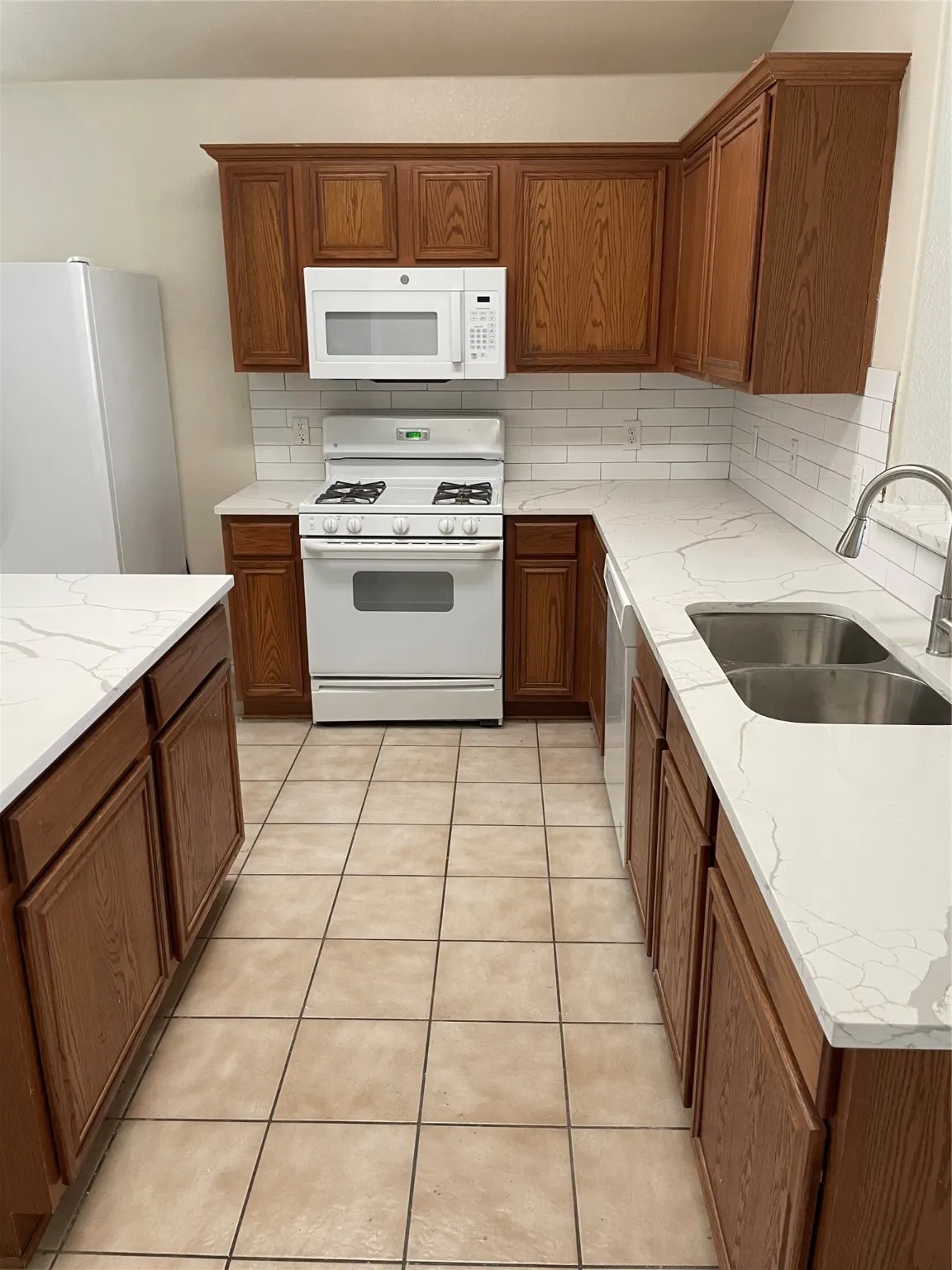Kitchen featuring refrigerator, sink, gas range gas stove, and tasteful backsplash