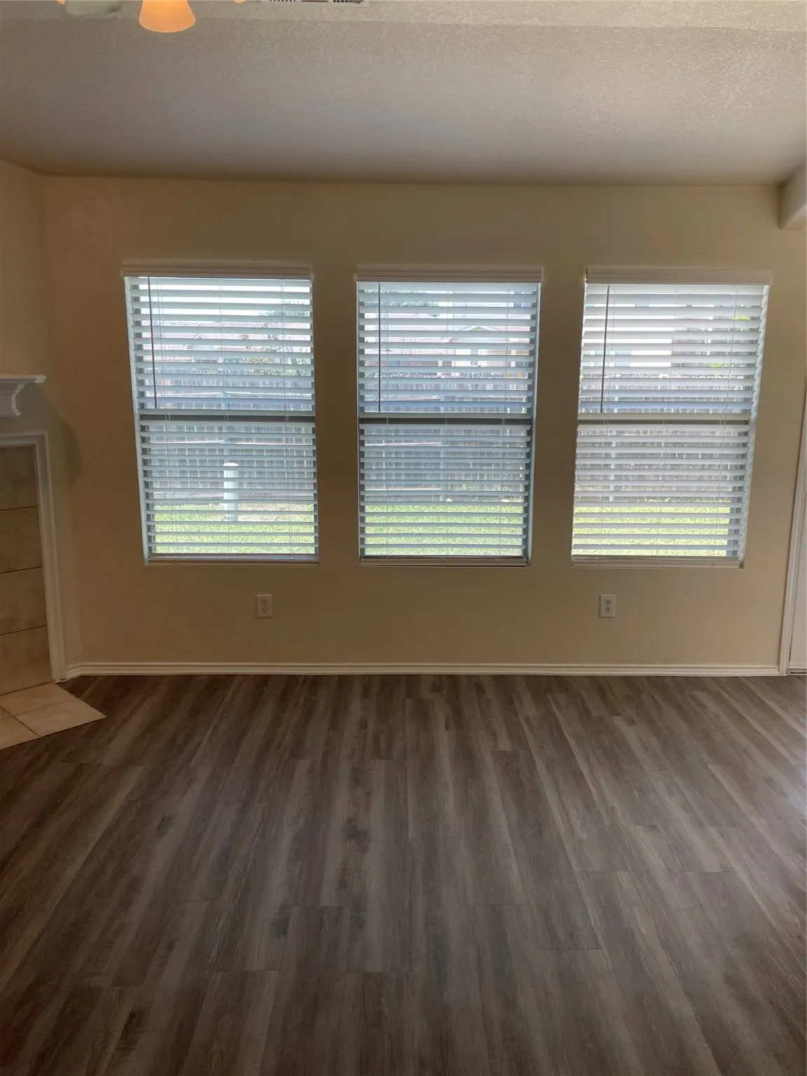 Unfurnished living room featuring ceiling fan, a textured ceiling, plenty of natural light, and dark hardwood / wood-style floors