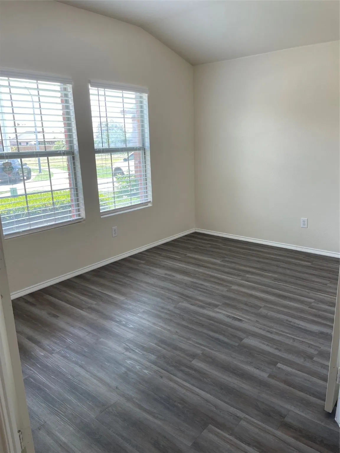 Empty room with vaulted ceiling and dark hardwood / wood-style floors