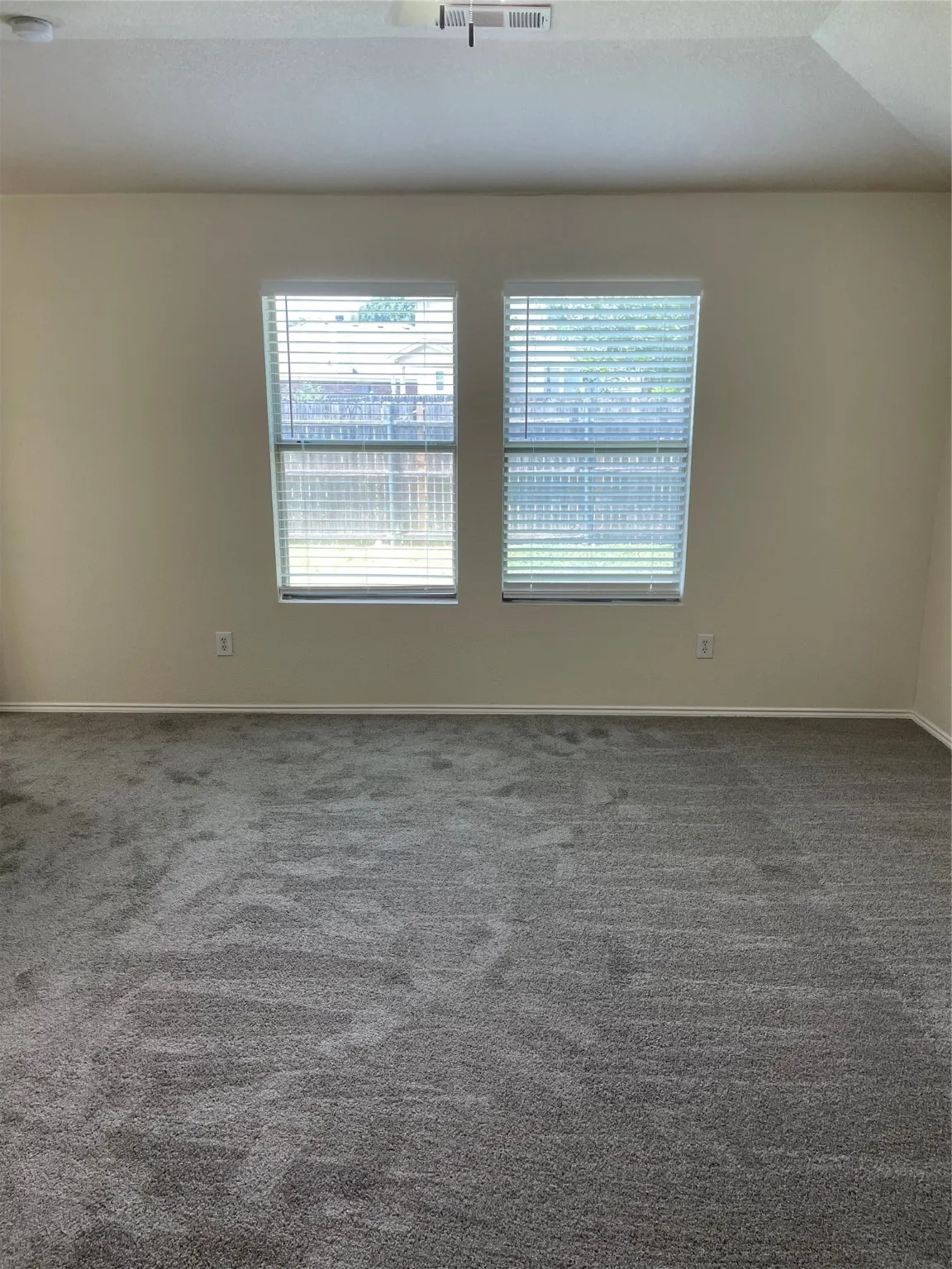 Carpeted empty room featuring vaulted ceiling