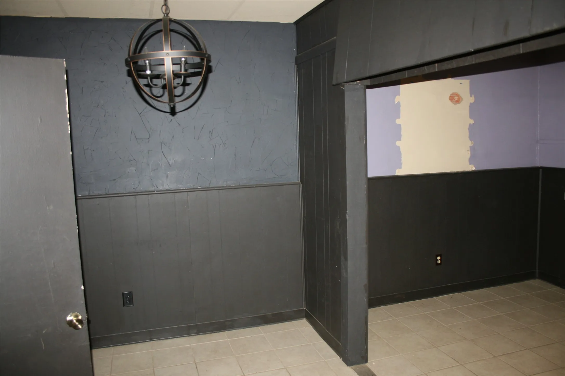 Empty room with light tile patterned floors and a chandelier