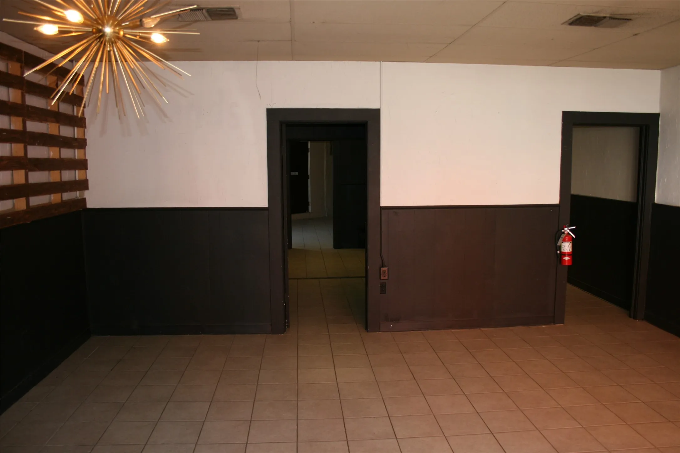 Tiled empty room featuring a notable chandelier