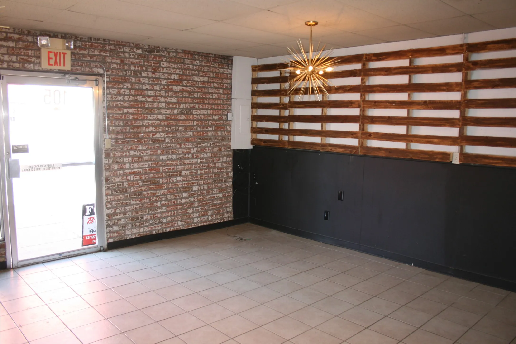 Spare room with brick wall and a chandelier