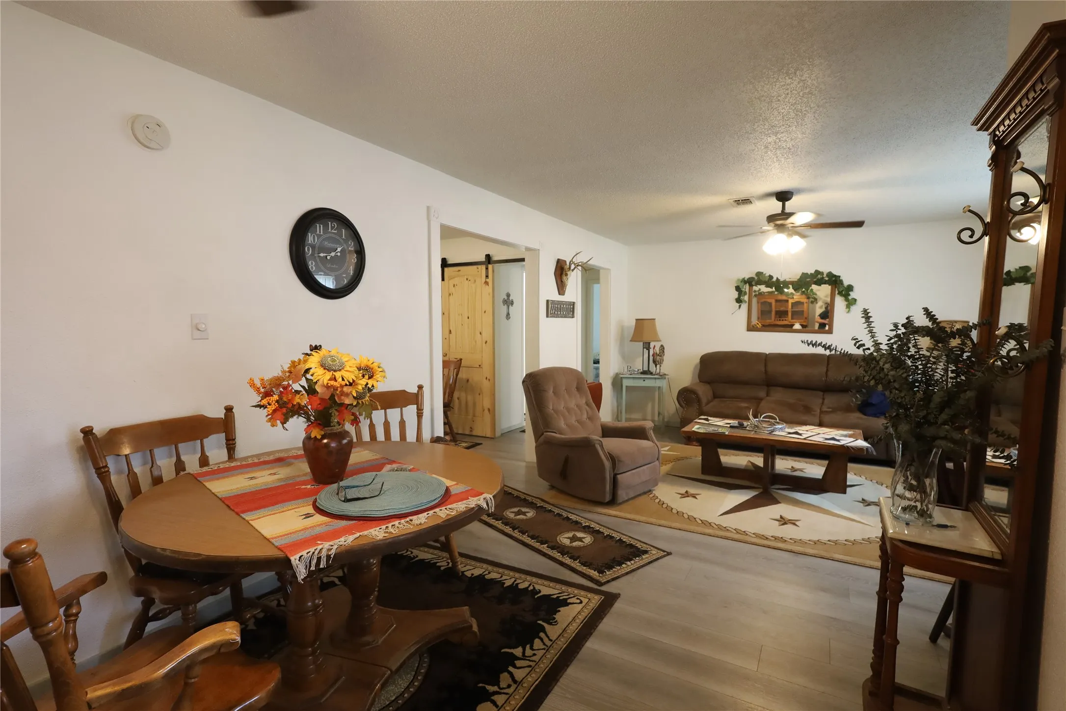 Dining room with ceiling fan, a textured ceiling, a barn door, and hardwood / wood-style floors