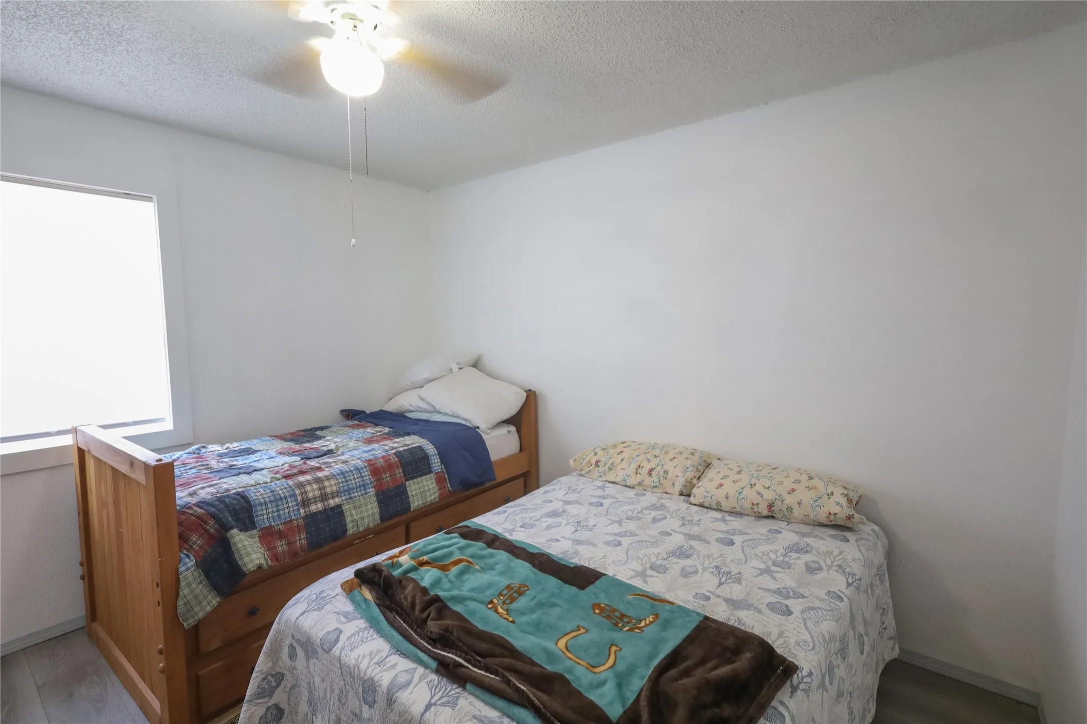 Bedroom featuring a textured ceiling, hardwood / wood-style flooring, and ceiling fan