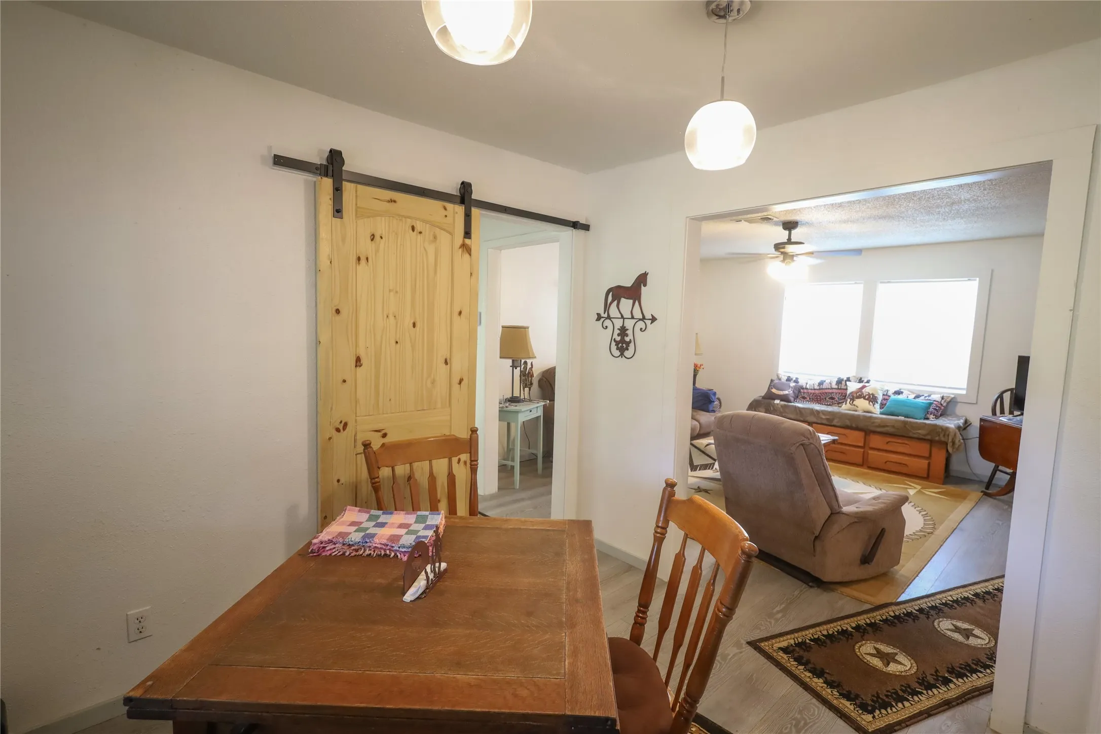 Dining space with a barn door, wood-type flooring, and ceiling fan